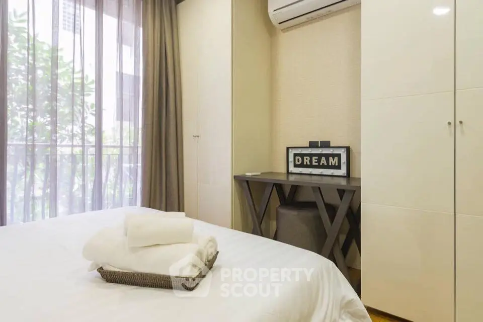 Cozy bedroom with modern decor and natural light, featuring a stylish desk and air conditioning.