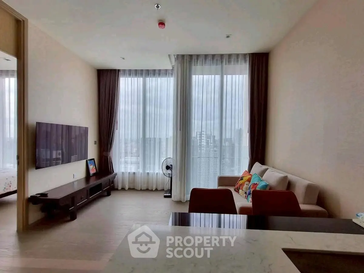 Spacious modern living room with large windows and city view, featuring elegant furniture and natural light.