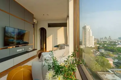 Luxurious living room with stunning city view through large window, modern decor and cozy seating.