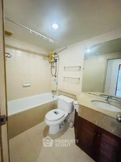 Spacious bathroom with bathtub and modern fixtures in a well-lit apartment.