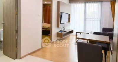 Modern living room with open layout and natural light, featuring a wall-mounted TV and stylish furniture.