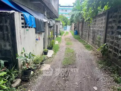 Charming alleyway leading to a residential property with lush greenery and rustic charm.