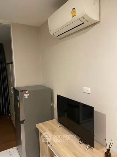 Modern apartment interior with air conditioner, TV, and refrigerator in a cozy living space.