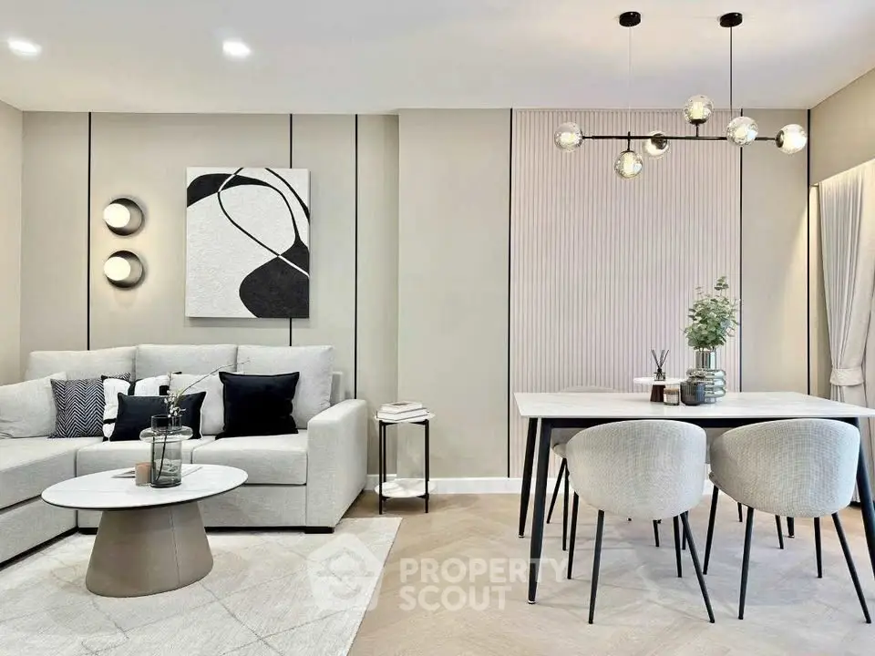 Modern living room with stylish decor and dining area, featuring contemporary lighting and elegant furniture.
