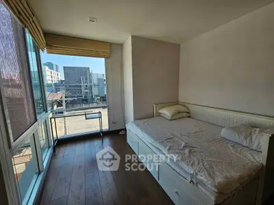 Cozy bedroom with large window and wooden flooring, perfect for natural light lovers.