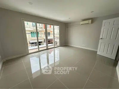 Spacious unfurnished room with glossy tiled floors and large windows in modern apartment.