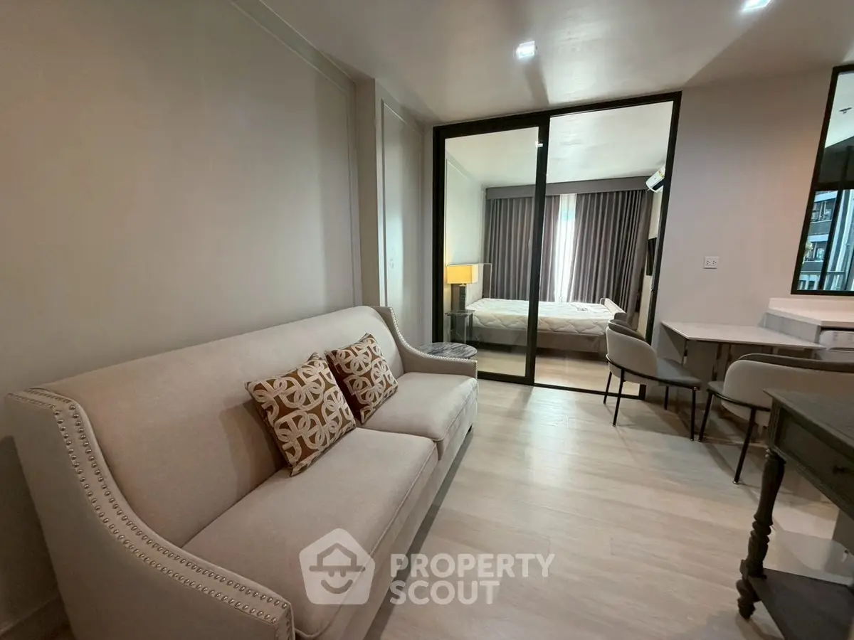 Modern living room with elegant sofa and view into cozy bedroom