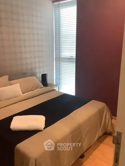 Cozy bedroom with modern decor and natural light through blinds.
