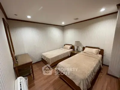 Cozy twin bedroom with wooden flooring and elegant lighting, perfect for a comfortable stay.