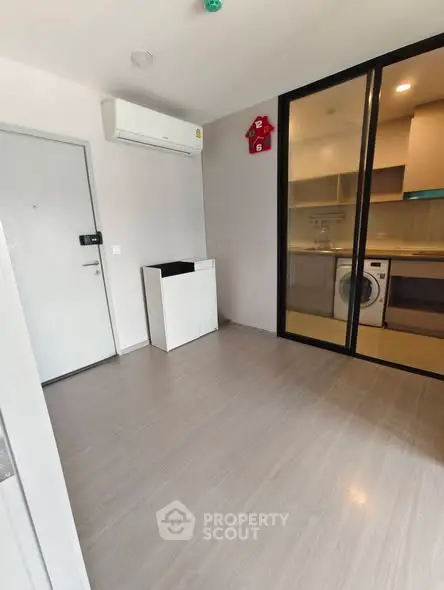 Modern apartment with sleek kitchen and washing machine, featuring sliding glass doors and air conditioning.