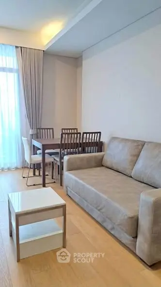 Modern living room with cozy sofa and dining area, featuring elegant curtains and wooden flooring.