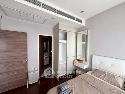 Modern bedroom with sleek furniture and ensuite bathroom in a stylish apartment.