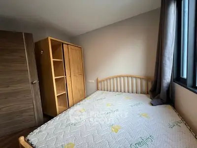 Cozy bedroom with wooden furniture and large window for natural light.