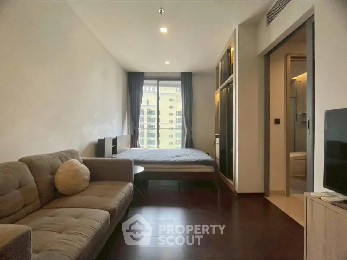 Modern studio apartment with cozy living area and large window view.