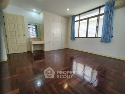 Spacious bedroom with polished wooden floors and ample natural light.
