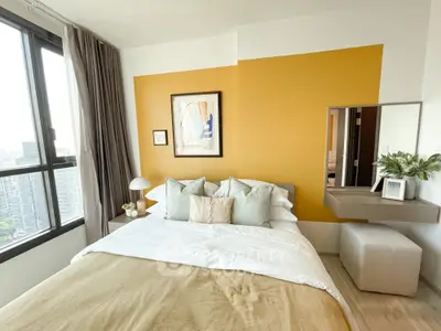 Modern bedroom with stylish decor and large window offering city views.