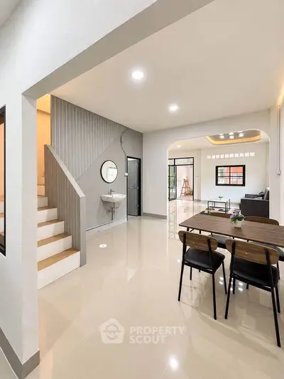 Modern open-plan living and dining area with sleek staircase and stylish decor.