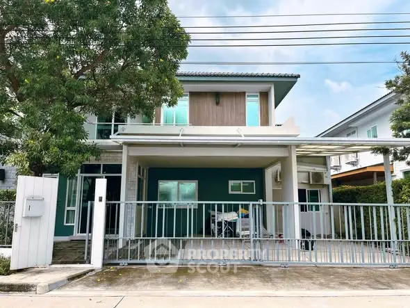 Modern two-story house with gated driveway and lush greenery, perfect for family living.