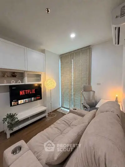 Cozy living room with modern decor, featuring a plush sofa, wall-mounted TV, and stylish lighting.