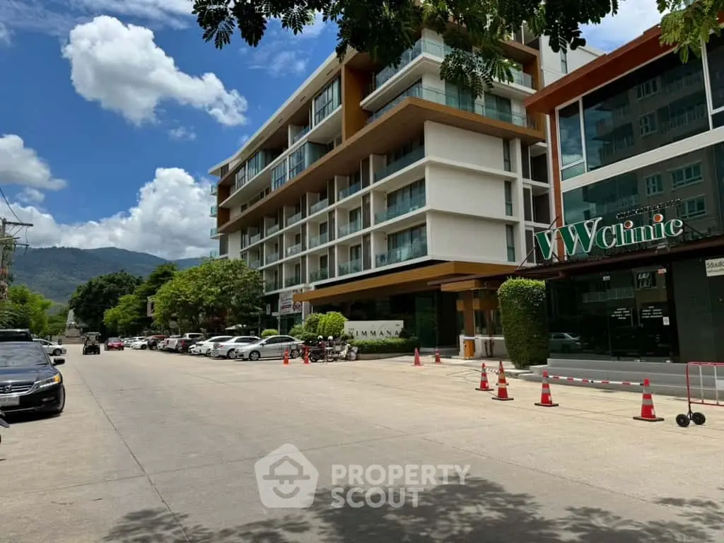 Modern apartment building with street view and parked cars under a clear blue sky.