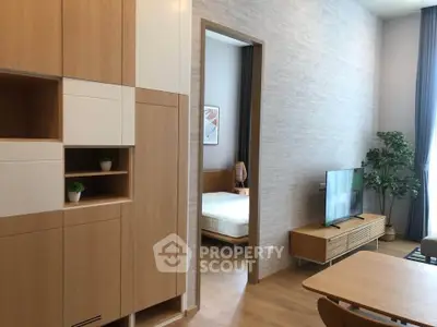 Modern living room with wooden furniture and view into a cozy bedroom