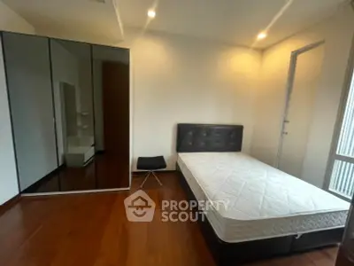 Spacious bedroom with modern design, featuring a large mirrored wardrobe and sleek wooden flooring.