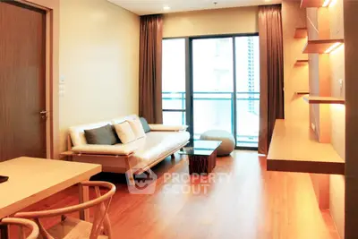 Modern living room with wooden flooring, stylish furniture, and large window for natural light.