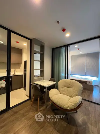 Modern apartment interior with open living and dining area, featuring stylish furniture and a view into the bedroom.