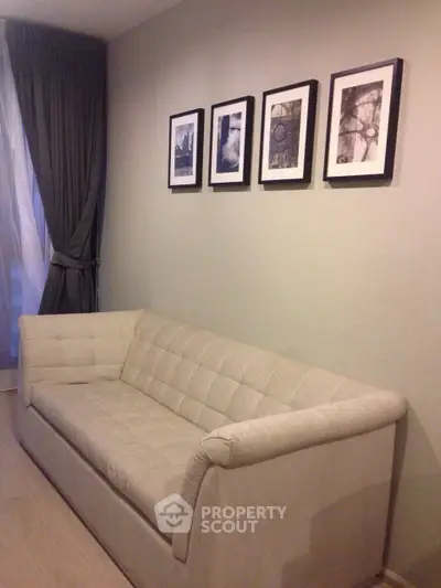 Cozy living room with elegant sofa and framed art on wall, perfect for relaxation.