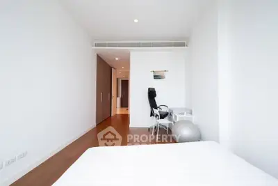 Spacious modern bedroom with study area and exercise ball, featuring sleek wooden flooring.