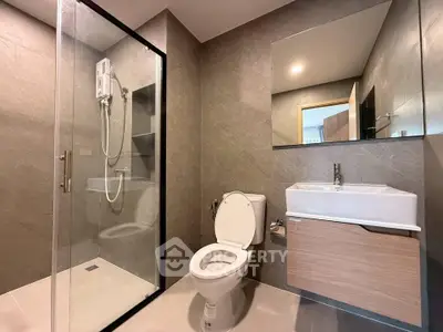 Modern bathroom with glass shower and sleek fixtures in contemporary apartment.