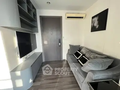 Modern living room with sleek furniture and wall-mounted TV, featuring stylish decor and air conditioning.
