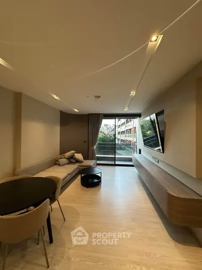 Modern living room with sleek furniture and large window leading to a balcony with a view.