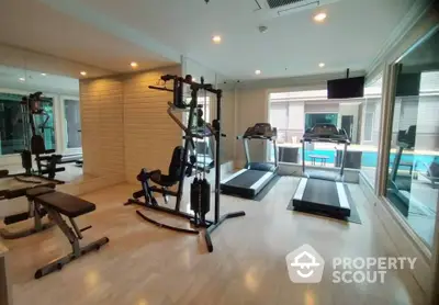 Modern gym with state-of-the-art equipment and pool view in luxury real estate property.