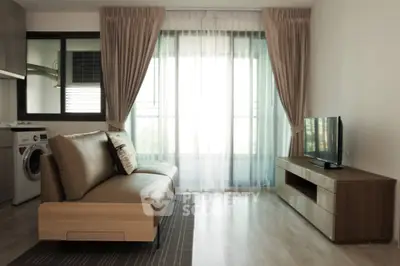 Modern living room with sleek sofa and TV, featuring washing machine in open layout.