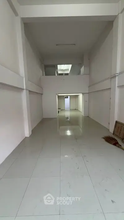 Spacious open-plan interior with high ceilings and tiled flooring, ideal for versatile use.