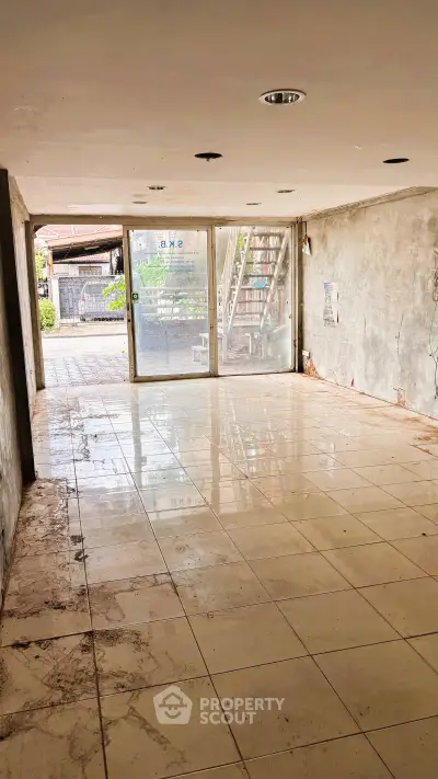 Spacious unfinished interior with tiled flooring and large glass doors, ideal for customization.