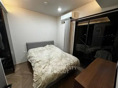 Cozy bedroom with modern air conditioning and large window offering night city view.