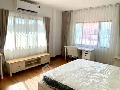 Bright and airy bedroom with large windows and modern furniture, perfect for relaxation.