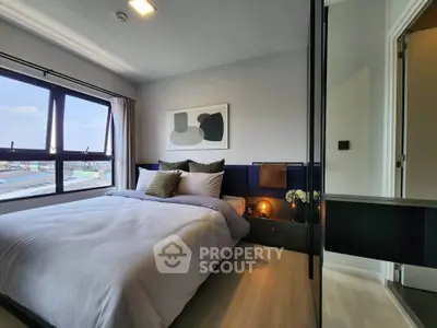 Modern bedroom with large window and stylish decor in a high-rise apartment.