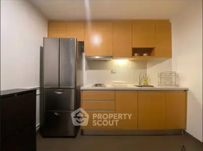 Modern kitchen with sleek cabinetry and stainless steel fridge in a compact layout.