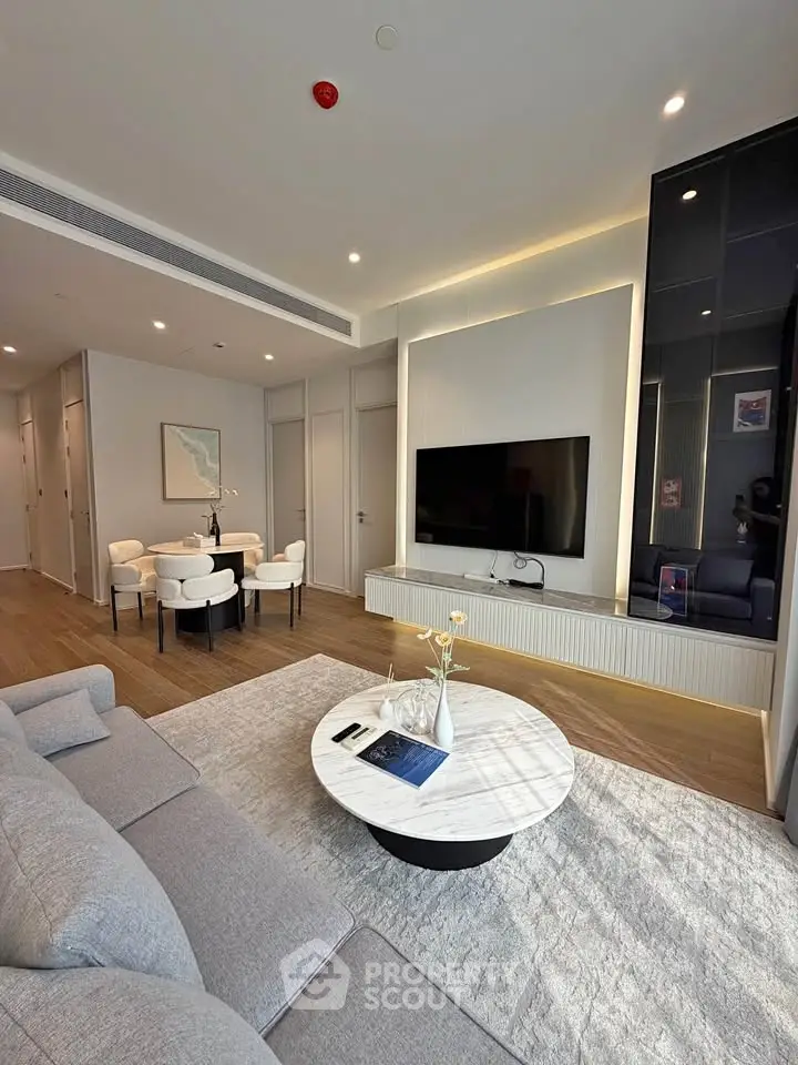 Modern living room with sleek design and stylish furniture, featuring a wall-mounted TV and elegant decor.