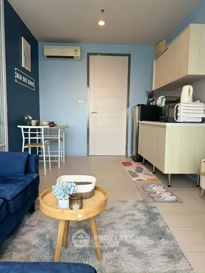 Modern living room with cozy blue sofa, stylish decor, and compact dining area in a chic apartment.