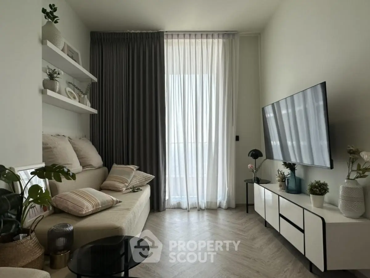 Modern living room with stylish decor and large TV, featuring elegant curtains and cozy seating area.