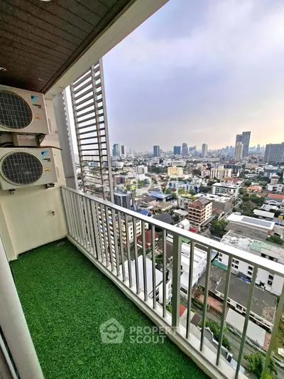 Stunning city view from a high-rise balcony with artificial grass flooring.
