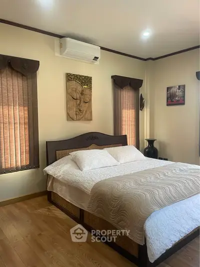 Cozy bedroom with elegant decor and air conditioning, featuring a comfortable bed and serene artwork.