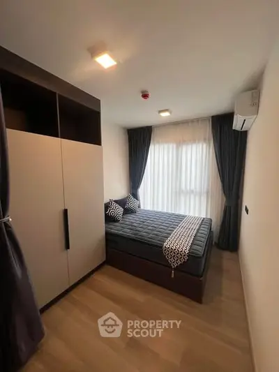 Modern bedroom with stylish decor and ample natural light, featuring a cozy bed and sleek wardrobe.