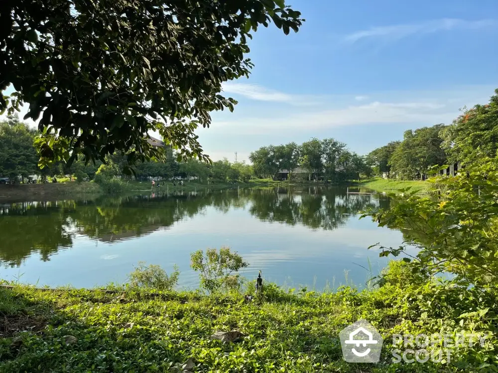 Serene lakeside view with lush greenery and clear blue sky, perfect for tranquil living.