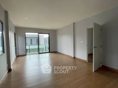 Spacious modern living room with wooden flooring and balcony access