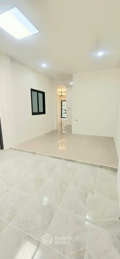Spacious modern interior with sleek tile flooring and bright lighting, ideal for versatile living space.